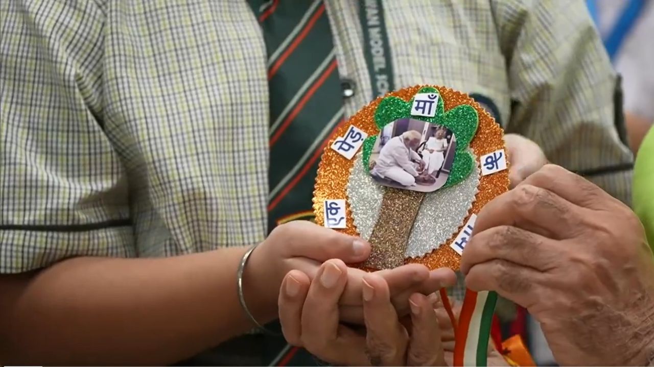 या राखीत मोदी यांची दिवंगत आई यांचा फोटो असून, मोदी हे आपल्‍या मातोश्रींचे पाय धूत असल्‍याचा फोटो देखील आहे. 