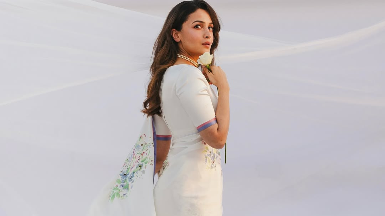 सब्यासाचीने डिजाईन केलेली ही प्रिंटेड व्हाईट साडी आलियावर खूपच सुंदर दिसतेय. तर आलियाने या साडीसह डीप व्ही नेक गळ्याचा ब्लाऊज घातला असून अगदी जुन्या हिरॉईनसारखा लुक ठेवण्याचा प्रयत्न केलाय